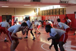 Varsity wrestlers warm up by practicing stances and transitions.