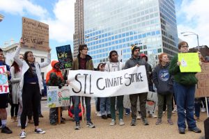 Strikers hold a large sign that reads STL Climate Strike.