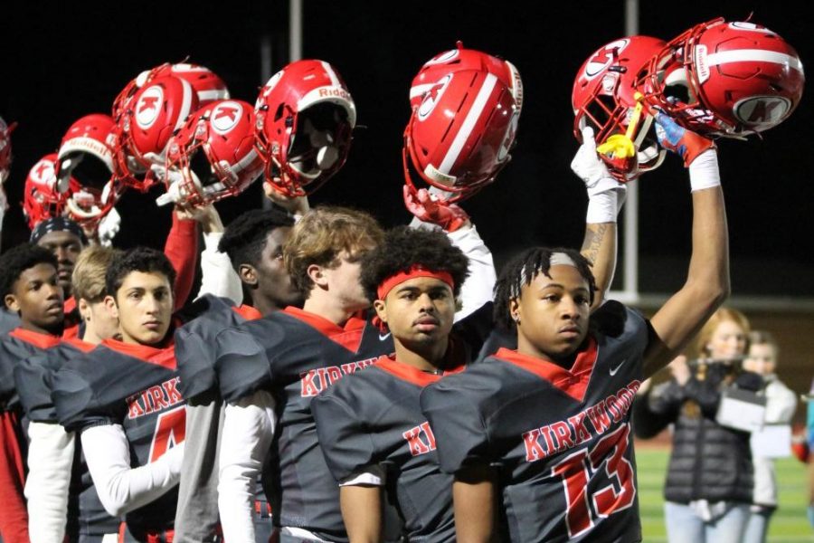 Juniors Mekhi Macklin (13) and Cole Johnson stand at the front of the line as the Pioneers raise their helmets at the end of the national anthem.