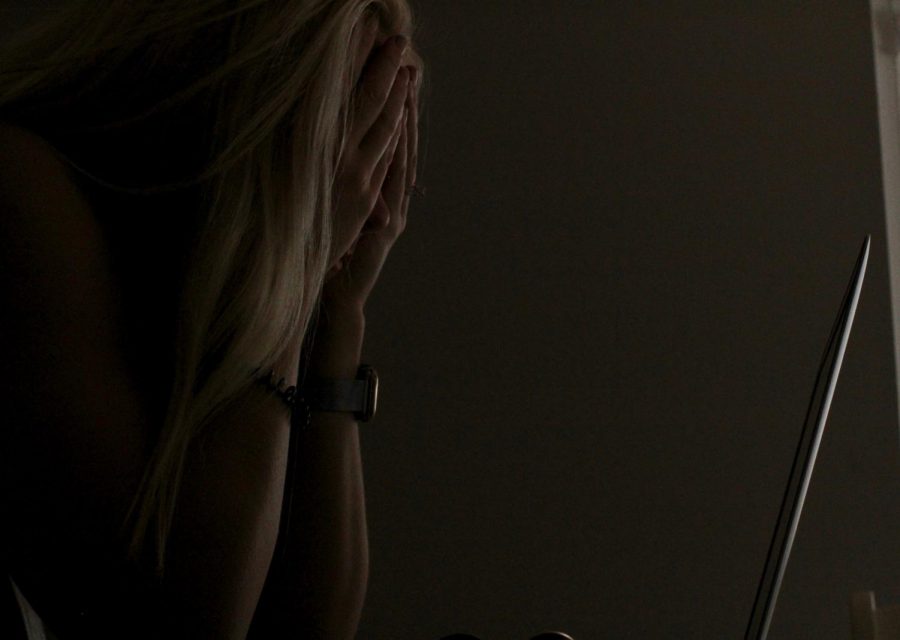 A student holds their head in their hands, as she tries to do her work. 