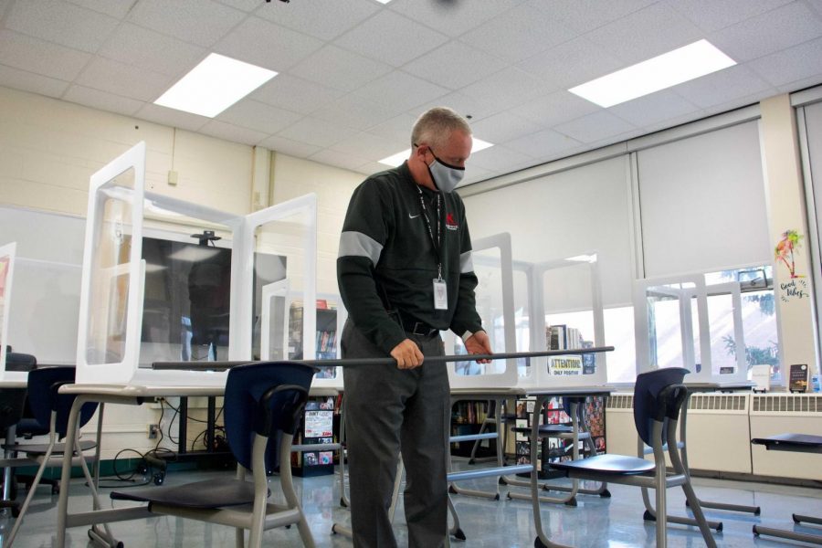 Dr. Michael Havener follows contract tracing procedures by measuring 6 feet between desks after a positive test.