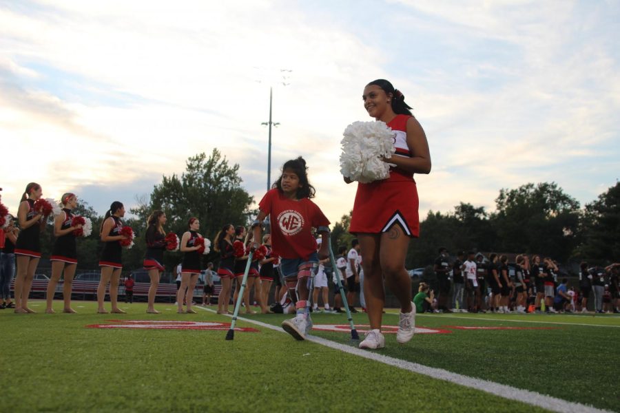Jaida Autry, senior, walks a Unified Night Lights member up the field to start off the night.