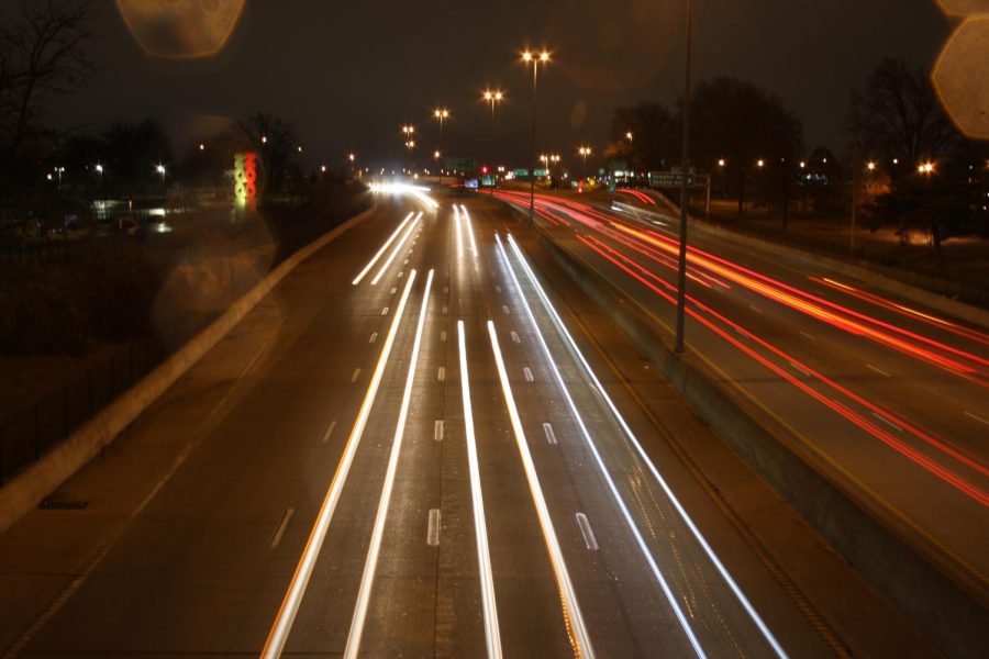 Cars rush by on the highway leaving trails of light captured by long exposure. 