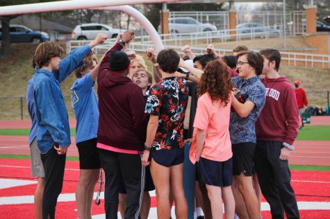 The boys distance team forms a huddle at the end of practice.