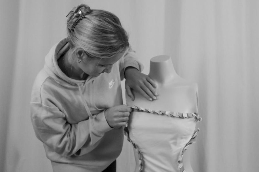 Anna McGinnis, junior, alters the dress she designed on a mannequin.