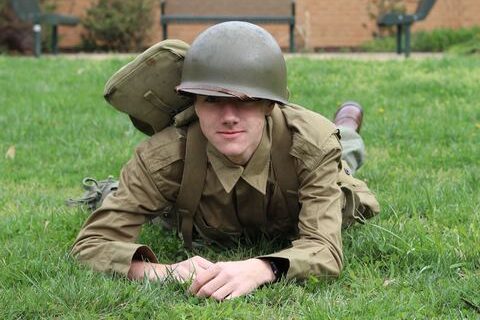 Nick DePalma army crawls through a field in typical uniform.