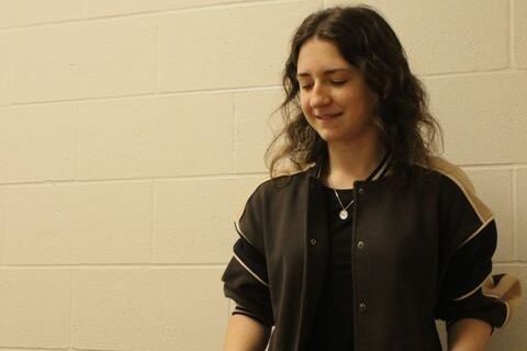 Lily Mitchell smiles while practicing her music in the band room.