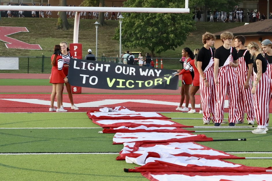 The cheerleaders hold the sign as they wait for the football players.