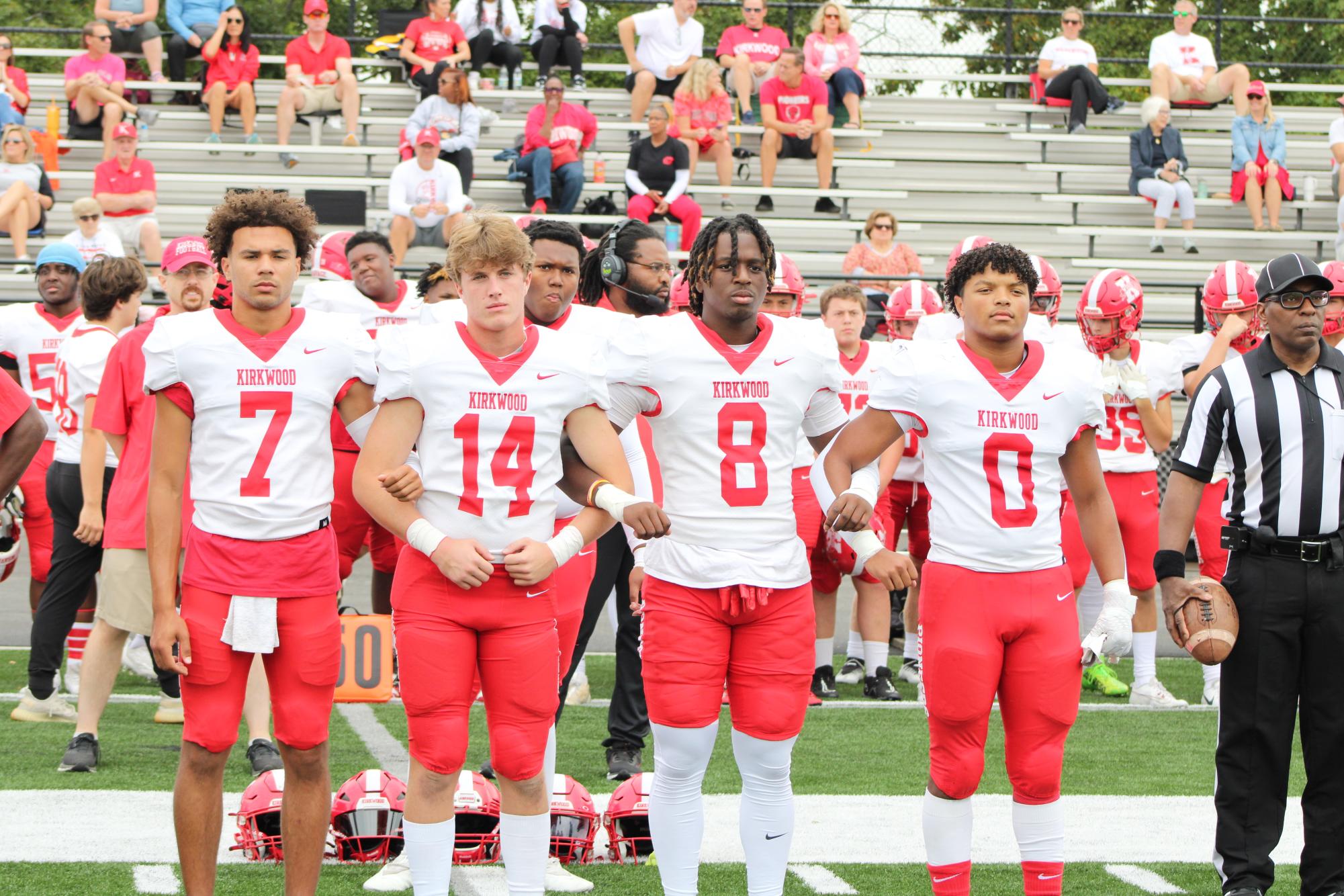 Senior football players stand as captains before their game.